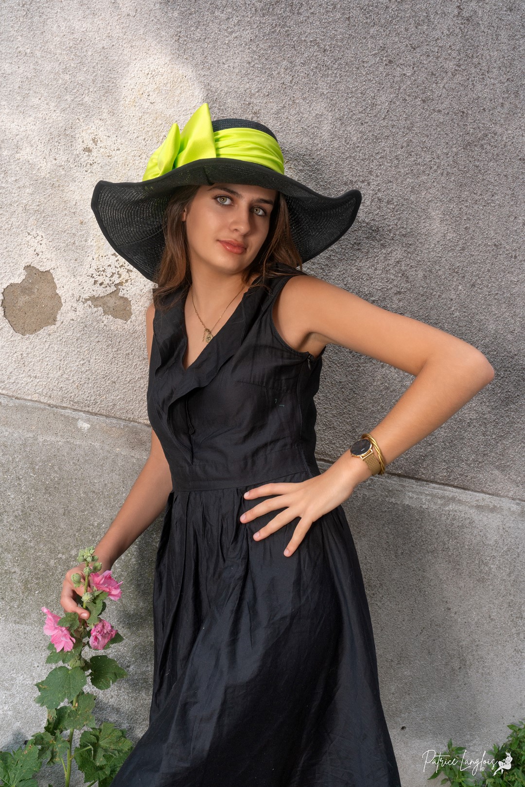 Grande capeline noire ornée d'un ruban vert vif.